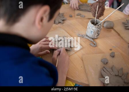 Varsovie, Pologne, Pologne. 24th avril 2022. Les enfants font des sculptures de tournesol à partir d'argile le 24 avril 2022 à Varsovie, Pologne. Quelques dizaines d'Ukrainiens et de Polonais ont pris part à un déjeuner d'intégration de Pâques organisé par le producteur polonais de céramique Cepelia (Acronyme pour le siège de l'industrie folklorique et artistique) et activiste du COLLECTIF STUS à l'occasion du dimanche orthodoxe de Pâques, Dans le but d'intégrer la communauté polonaise et ukrainienne à Varsovie, en Pologne. Un atelier d'argile pour les enfants a suivi le déjeuner. (Image de crédit : © Aleksander Kalka/ZUMA Press Wire) Banque D'Images