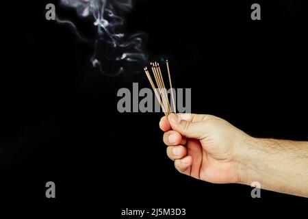 Jeu de bâtons d'encens couvants avec fumée aromatique sur fond sombre Banque D'Images