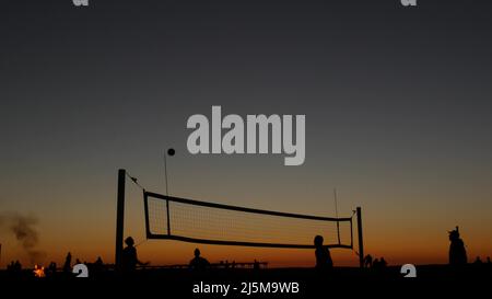 Silhouette de filet de volley-ball sur le terrain de sport de plage au coucher du soleil, les gens jouant sur la côte de Californie, États-Unis. Terrain de sport pour les joueurs de volley-ball sur la côte de l'océan. Ciel crépuscule de Mission Beach, San Diego. Banque D'Images