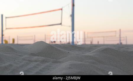 Joueurs jouant au volley-ball sur la plage, jeu de volley-ball avec balle et filet, silhouette de palmiers au coucher du soleil, côte californienne, États-Unis. Des gens défocused sur la rive sablonneuse de l'océan. Cinémagraphe sans couture. Banque D'Images