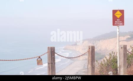 Falaise instable abrupte, roche ou bluff, temps brumeux, érosion de la côte de Californie, États-Unis. Le crag érodé de Torrey Pines donne sur le point de vue, les vagues de l'océan d'en haut. Garde-corps de chaîne pour trekking de sécurité, signe de danger. Banque D'Images