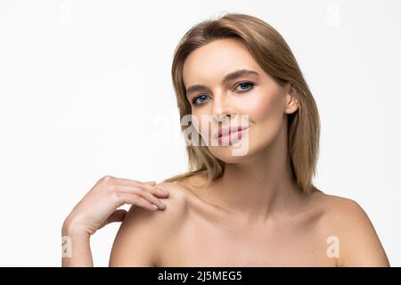 Femme de beauté. Belle jeune femme touchant sa peau. Portrait isolé sur fond blanc. Soins de santé. Une peau parfaite. Banque D'Images