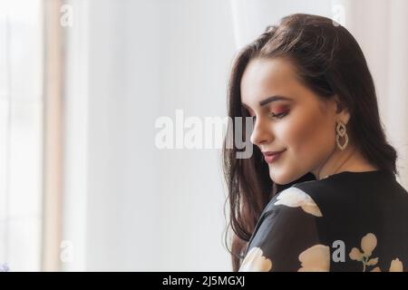 Vue latérale d'une jolie fille souriante avec des yeux abaissés à l'intérieur. Horizontalement. Banque D'Images