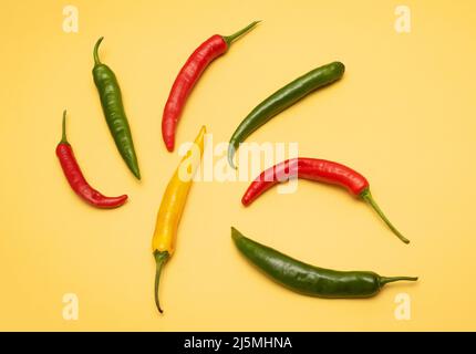 Piment coloré et poivrons habanero chauds en cercle sur fond jaune Banque D'Images
