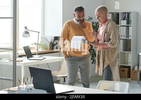 De jeunes collègues interraciaux réfléchis de SMART cas discutent du contenu du contrat Banque D'Images