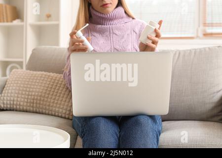 Belle femme tenant le traitement pour le mal de gorge et de chat vidéo avec le médecin à la maison Banque D'Images
