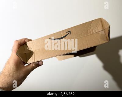 Paris, France - 24 avr 2022: POV main mâle tenant contre le mur héros objet tourné du logotype Amazon Prime sur la nouvelle boîte de carton lecteur Banque D'Images