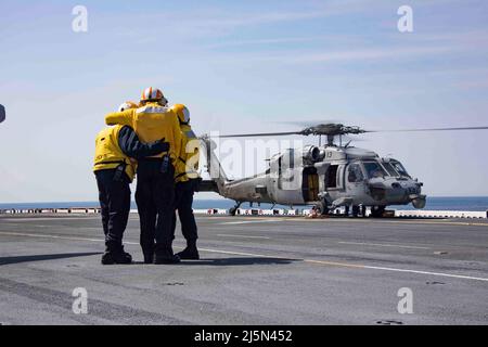 220423-N-LZ839-1154 NORFOLK, VIRGINIE. (Le 23 avril 2022) - les marins affectés au navire d'assaut amphibie USS Bataan (LHD 5), observent comme un hélicoptère MH-60s affecté au Chargers of Helicopter Sea combat Squadron (HSC) 26, qui se prépare à prendre le pont de vol, le 23 avril 2022. Bataan est en cours dans la zone d'exploitation de la flotte de 2nd. Bataan est à la base navale de Norfolk. (É.-U. Photo de la marine par le spécialiste des communications de masse 3rd classe Darren Newell) Banque D'Images