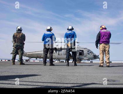 220423-N-LZ839-1197 NORFOLK, VIRGINIE. (Le 23 avril 2022) - les marins affectés au navire d'assaut amphibie USS Bataan (LHD 5), se tiennent debout comme un hélicoptère MH-60s affecté au navire de combat en mer des Chargers of Helicopter Sea combat Squadron (HSC) 26, se prépare à partir, le 23 avril 2022. Bataan est en cours dans la zone d'exploitation de la flotte de 2nd. Bataan est à la base navale de Norfolk. (É.-U. Photo de la marine par le spécialiste des communications de masse 3rd classe Darren Newell) Banque D'Images