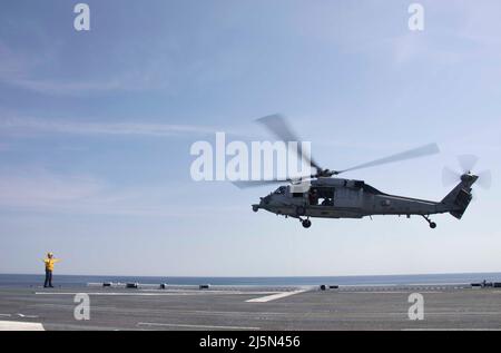 220423-N-LZ839-1400 NORFOLK, VIRGINIE. (Le 23 avril 2022) - Un marin affecté au navire d'assaut amphibie USS Bataan (LHD 5) dirige un hélicoptère MH-60s affecté à l'escadron de combat de la mer (HSC) 26 de Chargers of Helicopters pendant les opérations de vol, le 23 avril 2022. Bataan est en cours dans la zone d'exploitation de la flotte de 2nd. Bataan est à la base navale de Norfolk. (É.-U. Photo de la marine par le spécialiste des communications de masse 3rd classe Darren Newell) Banque D'Images