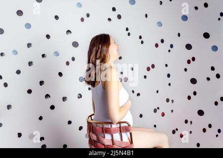 Femme enceinte assise sur une chaise. Vue arrière. Banque D'Images