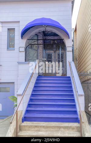 Extérieur de la maison avec des palettes pourpres à San Francisco, Californie. Il y a un escalier à l'avant menant à la porte en fer voûté avec la voûte. Banque D'Images