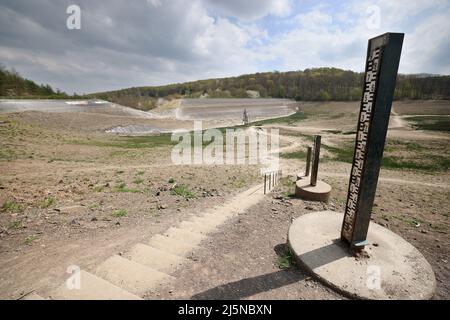 22 avril 2022, Rhénanie-du-Nord-Westphalie, Bad Münstereifel: Un cran (l) peut être vu dans le barrage du réservoir Steinbach derrière les indicateurs de niveau d'eau. Après la menace de rupture du barrage lors de l'inondation de juillet 2021, un canal a été construit dans le barrage par lequel l'eau peut s'écouler pendant les niveaux élevés. (À dpa: «Après le danger de l'éclatement du barrage: Le canal de drainage pour le barrage Steinbach est presque terminé») photo: Oliver Berg/dpa Banque D'Images