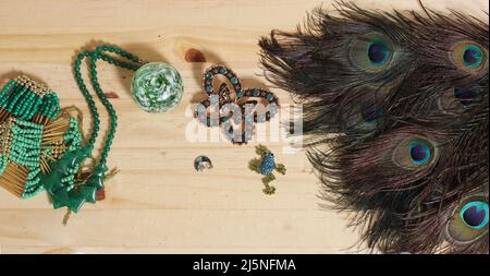 Plumes de paon avec perles vertes et brocher de papillons de cuivre et de vert sur table en bois Banque D'Images