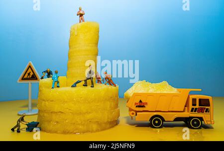 Mini-hommes de construction miniature travaillant sur un ananas. Trancher et couper. Banque D'Images