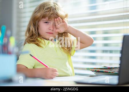 Fatigué triste garçon d'école en faisant des devoirs. Enfant tenir un crayon et dessiner à la maison. Un jeune garçon qui dessine à la table. Banque D'Images