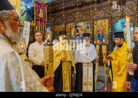 Nazareth, Israël - 23 avril 2022 : le service du samedi Saint de Pâques prie dans l'Église orthodoxe grecque de l'Annonciation, avec les prêtres tenant le F Saint Banque D'Images