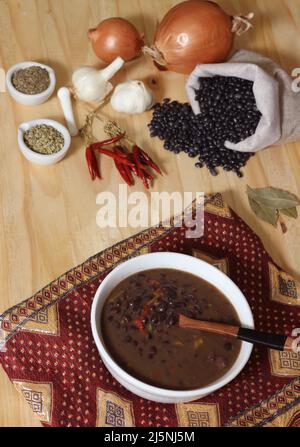 Piment noir sur table en bois avec épices et haricots noirs séchés Banque D'Images