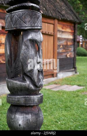 Poste de Hitching sur fond de maison de l'ail. Poteau en bois à lequel un cheval est attaché pour l'empêcher de se départir, sculpté d'une bûche en forme de WO Banque D'Images