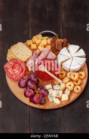 Tableau des hors-d'œuvre avec assortiment de fromages, viande, rosette à saucisse, raisin et biscuits salés. Assiette de charcuterie et fromage. Vue de dessus Banque D'Images