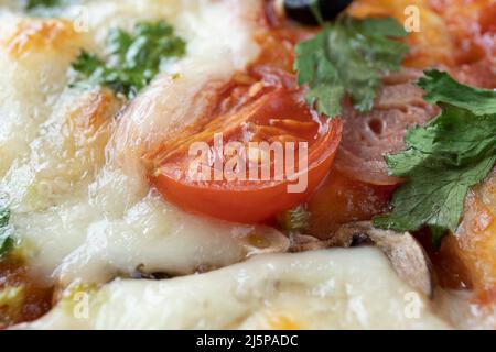 Macro-shot de pizza italienne avec mozzarella et tomates cerises, champignons et oignons rouges, épices, ketchup et paprika. Cuisine italienne. Banque D'Images