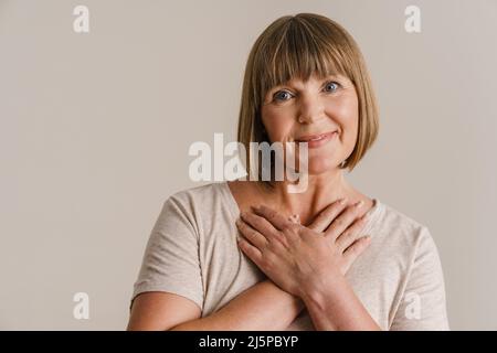 Femme blonde senior souriant et regardant la caméra isolée sur un mur blanc Banque D'Images