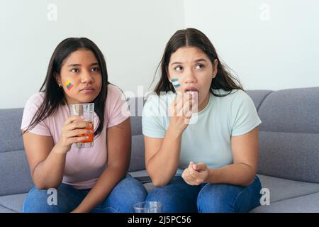 Des amies latino-américaines regardant un match de football à la maison Banque D'Images