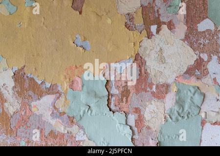 Plusieurs anciennes couches de peinture de différentes couleurs sur le mur, la texture du mur abîmé Banque D'Images