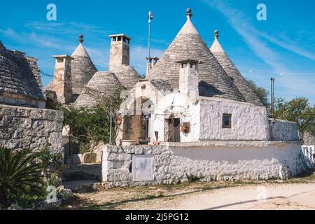 Groupe de belle maison Trulli ou Trullo, cabane traditionnelle en pierre sèche des Pouilles avec un toit conique et de vieux murs en pierre sèche à Puglia, en Italie, avec des plantes Banque D'Images