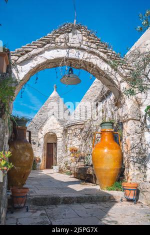 Belle maison Trulli ou Trullo, cabane traditionnelle en pierre sèche des Pouilles avec toit conique et ancienne arche en pierre sèche et murs à Puglia, Italie avec grand vase Banque D'Images