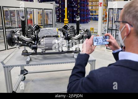 Meerane, Allemagne. 25th avril 2022. Un visiteur prend une photo du train arrière avec moteur électrique pour un véhicule électrique Volkswagen. La pose de la pierre de fondation du Hall 7 dans le Parc industriel de Meerane, le même jour, représente l'achèvement considérable du Parc industriel. Le hall logistique sert à agrandir l'assemblage d'essieux, qui se déroule de l'autre côté de la rue, presque à proximité de l'usine VW Mosel de Zwickau. C'est là que sont fabriqués les essieux des véhicules électriques du groupe VW. Credit: Jan Woitas/dpa/Alay Live News Banque D'Images