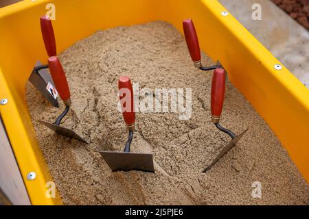 Meerane, Allemagne. 25th avril 2022. Les truelles sont encollées dans un seau de sable pour une cérémonie de pose de pierres de fondation pour le Hall 7 du Parc industriel de Meerane. La construction représente l'achèvement de grande envergure du parc industriel. Le hall logistique sert à agrandir l'assemblage d'essieux, qui se déroule de l'autre côté de la rue, presque à proximité de l'usine VW Mosel de Zwickau. C'est là que sont fabriqués les essieux des véhicules électriques du groupe VW. Credit: Jan Woitas/dpa/Alay Live News Banque D'Images