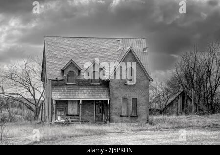 Une ancienne ferme noire et blanche abandonnée à l'aspect sinistre en hiver sur une cour de ferme dans les régions rurales du Canada Banque D'Images