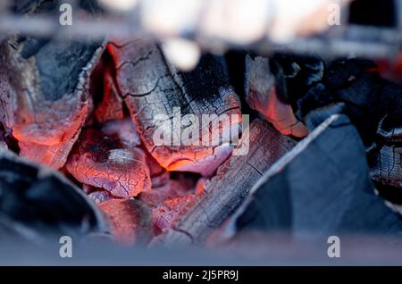 Les embres chauds du feu de bois en feu. Bois de chauffage brûlant sur le gril. Arrière-plan abstrait. Gros plan. Banque D'Images