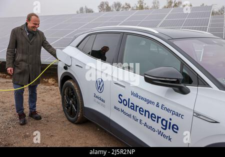 25 avril 2022, Saxe, Zwickau: Wolfram Günther (les Verts), ministre de l'énergie et de la protection du climat de Saxe, branche la fiche de recharge dans un VW ID.4 dans un nouveau parc solaire. Enerparc AG exploite le parc solaire Mosel de six hectares et fournira chaque année 5,5 millions de kWh d'énergie solaire au cours des 20 prochaines années pour la production des modèles Volkswagen entièrement électriques de Zwickau. Les trois sites Volkswagen en Saxe sont déjà alimentés en électricité verte à partir de l'hydroélectricité depuis la fin de 2017. Jusqu'à présent, cependant, cela vient d'Autriche. Zwickau est maintenant le premier endroit saxon à recevoir Banque D'Images