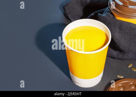 Soupe épaisse à la crème de citrouille végétalienne avec des graines dans une tasse jetable sur fond bleu foncé avec espace de copie. Concept de soupe à emporter, de nourriture à emporter et de la santé Banque D'Images