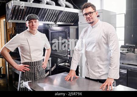 Portrait d'un chef confiant et d'un cuisinier regardant l'appareil photo tout en travaillant dans une cuisine commerciale Banque D'Images