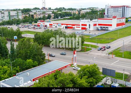 Kemerovo, Russie 24 juin 2021. Intersection urbaine où se trouve la station Lukoil et au loin un grand magasin du Magnit Retail Chai Banque D'Images