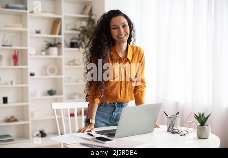 Bonne femme entrepreneur du Moyen-Orient debout près d'un ordinateur portable au bureau Banque D'Images