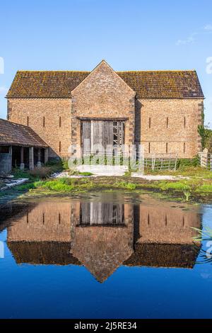 Une ancienne grange en briques se reflète dans une grande flaque dans le village Severnside d'Arlingham, Gloucestershire, Angleterre Banque D'Images