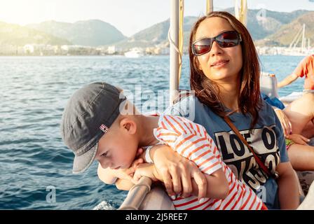 Mère et son aiment la voile sur le bateau après la côte de Marmaris. Femme en lunettes de soleil et enfant mignon en chapeau pendant les vacances d'été en Turquie vue rapprochée Banque D'Images