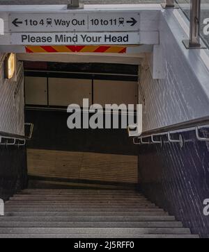 Entrée d'une station de métro. Les marches mènent à un passage et les panneaux sont en hauteur. Banque D'Images