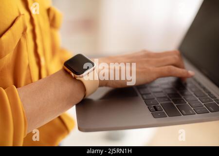 Lady utilisant la saisie d'ordinateur portable sur le clavier travail en ligne en intérieur, Cropped Banque D'Images