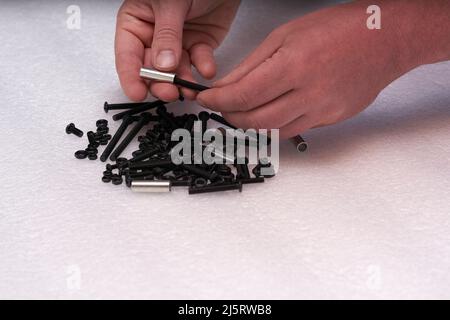 2 introduire le boulon à la main dans un manchon. Tas de boulons. Eléments de connexion pour l'industrie et l'artisanat. Banque D'Images