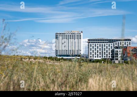 Warnemünde, le grand hôtel blanc Neptun en face d'un ciel bleu et nuageux. La prairie verte sur la dune de sable est au premier plan. Une belle terre naturelle Banque D'Images