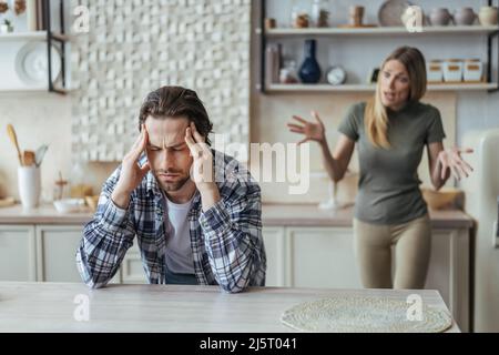 Un homme épris offensé du millénaire en Europe avec une barbe de trois jours tient la tête avec les mains, ignorant crier dame après scandale Banque D'Images