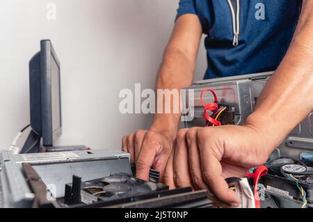 jeune homme dans une pièce travaillant sur la maintenance et la réparation d'ordinateur, personne non reconnaissable technicien d'ordinateur changer les composants du service d'ordinateur Banque D'Images