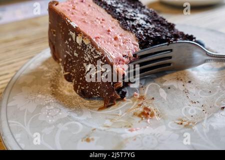 Fourchette coupant à travers un morceau de délicieux gâteau maison de fraise et de chocolat Banque D'Images