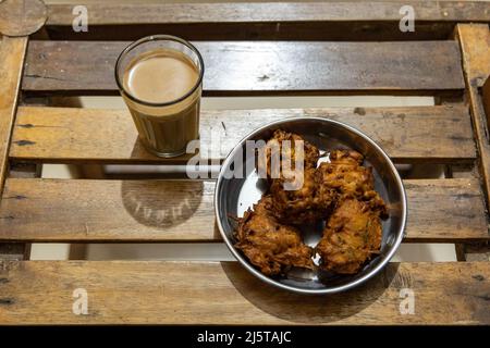 En-cas de thé commun combo de pakodas d'oignon servi avec une tasse de thé de masala Banque D'Images