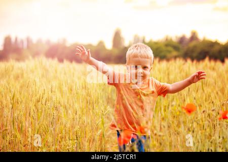 Les jeunes enfants blonds se tiennent dans le champ de blé en soulevant les mains Banque D'Images